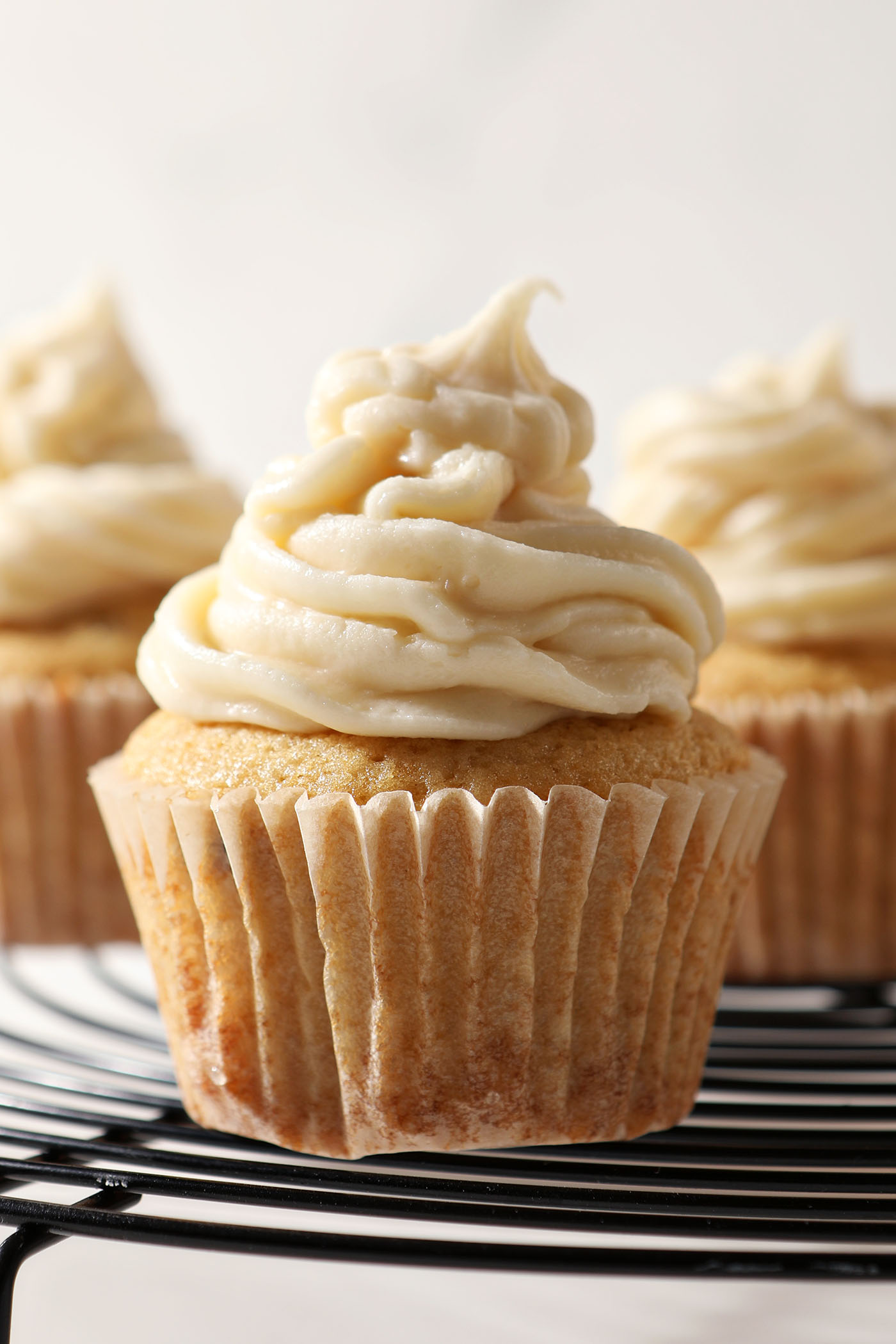 Close up of salted maple frosting on top of cupcakes on a cooling rack