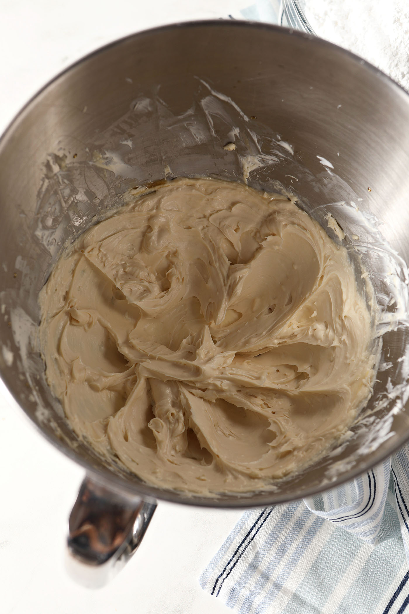 Creamed ingredients for salted maple frosting in a metal bowl on a white stone surface