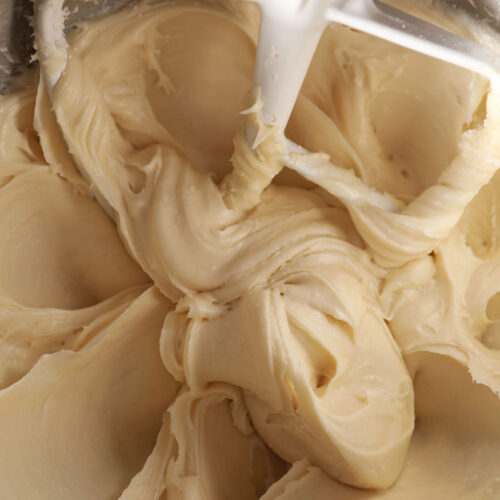 Close up of Salted Maple Frosting with a paddle attachment of a mixer in a metal bowl