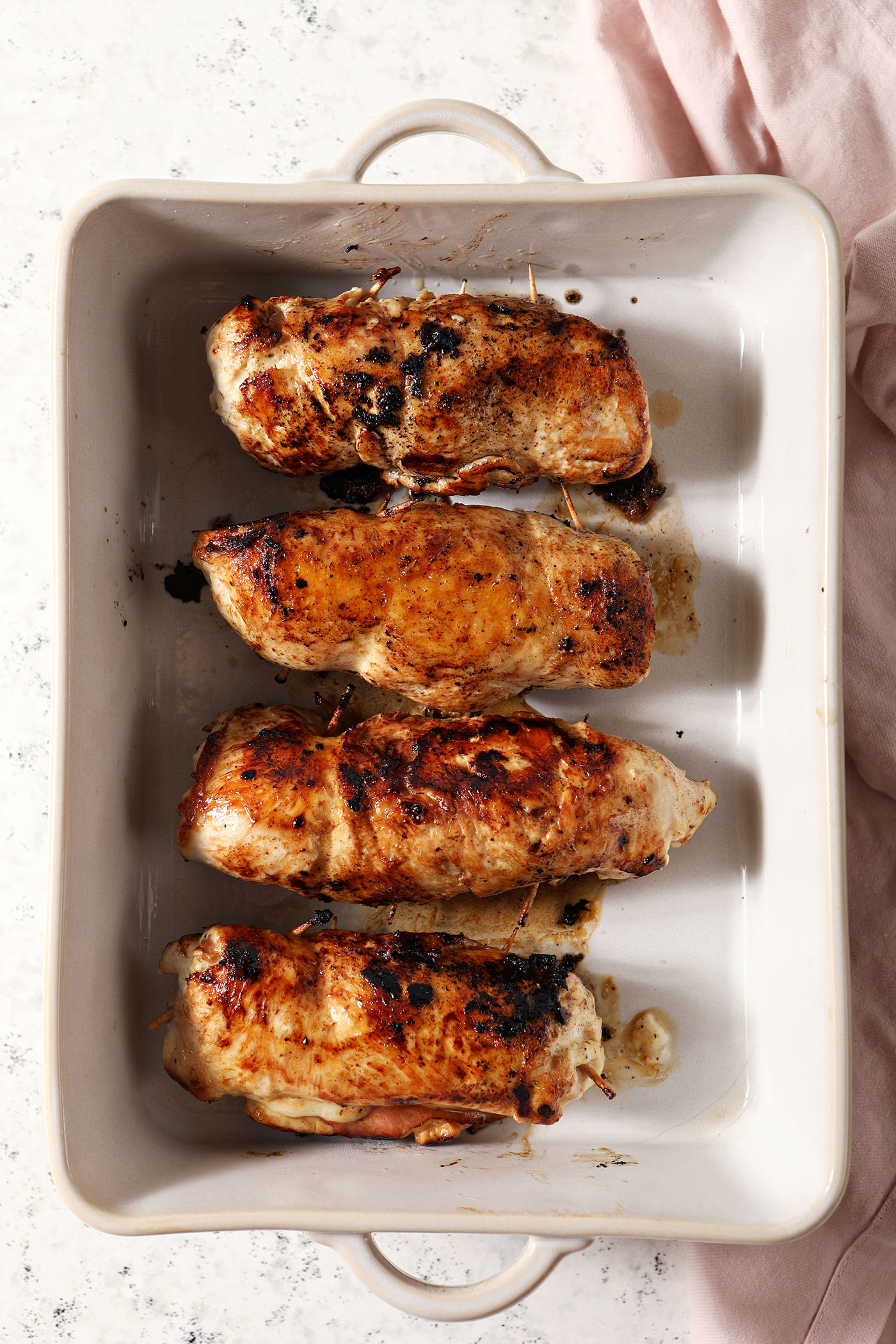 Four pieces of baked chicken cordon bleu in a casserole dish