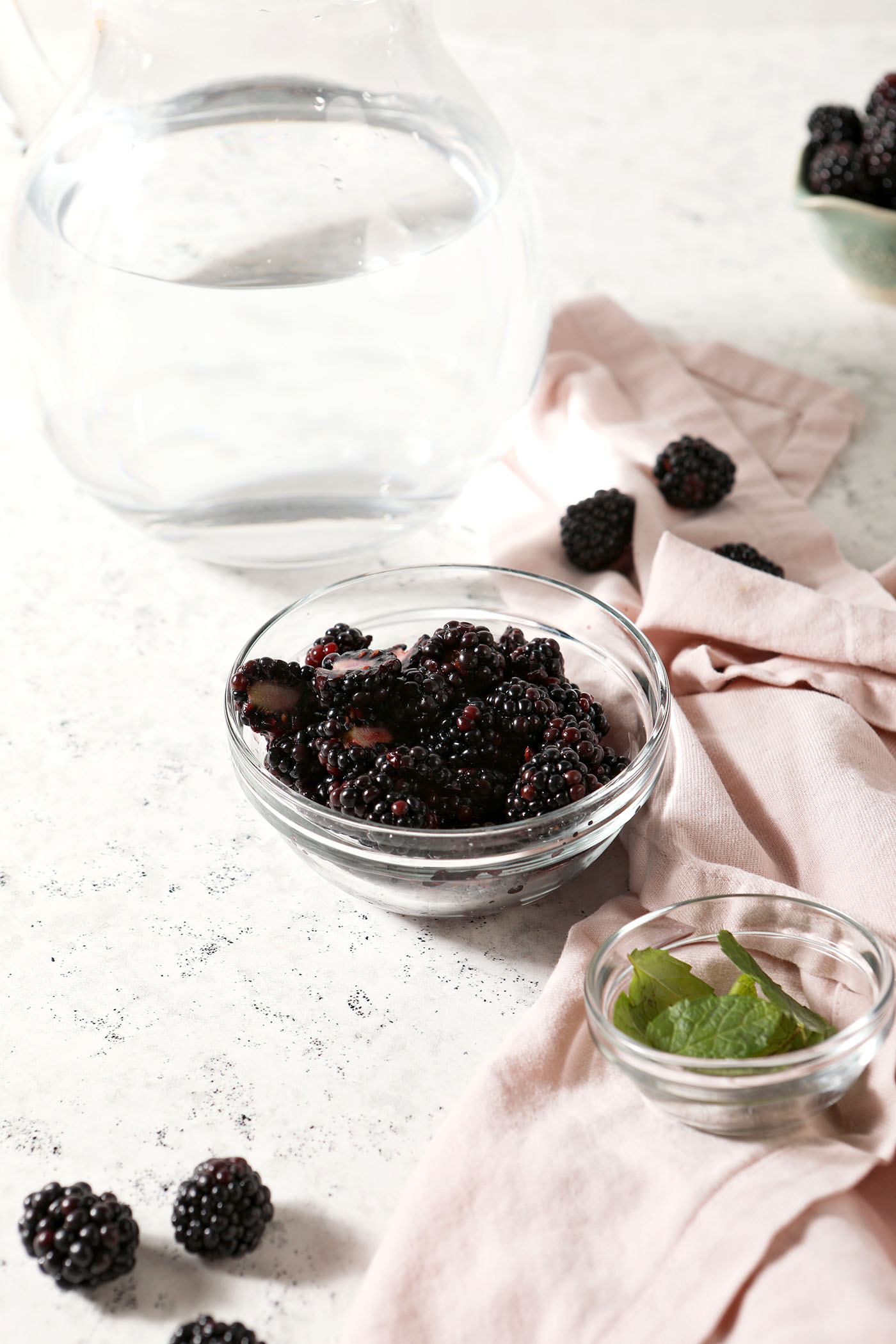 Bowls holding blackberries, mint leaves and water before mixing spa water