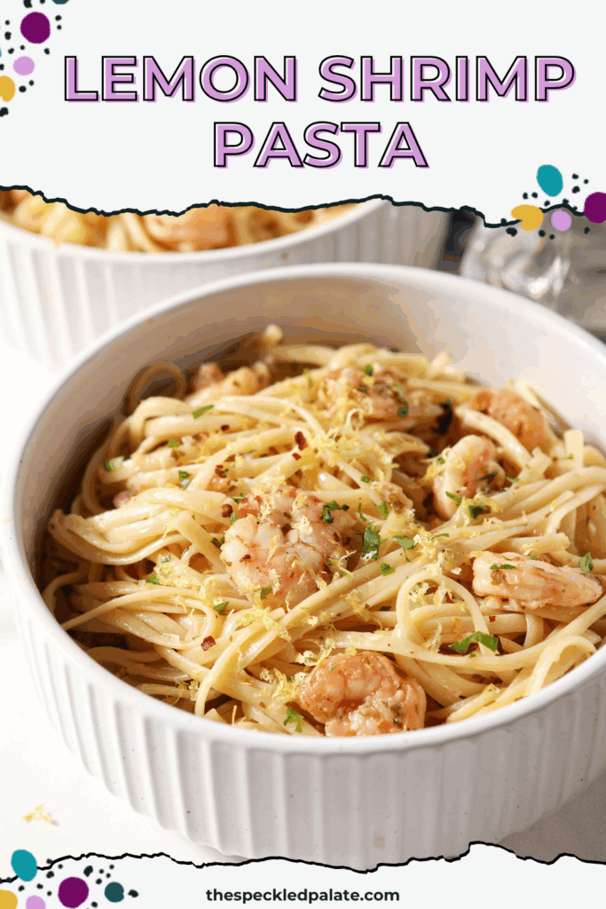 Two bowls holding garlicky lemon shrimp pasta on a white surface next to a blue striped linen, a glass of wine, fresh herbs, lemons and more with the text lemon shrimp pasta