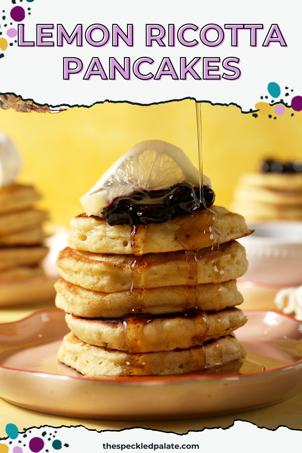 Maple syrup drizzles on top of a stack of lemon pancakes topped with blueberry compote and a lemon twist with the text lemon ricotta pancakes