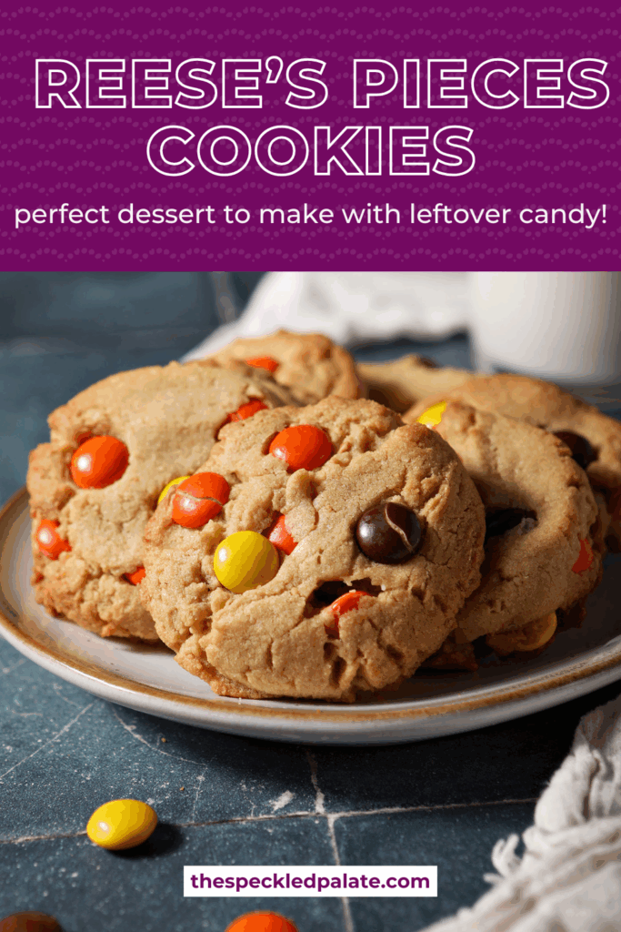 A plate of peanut butter cookies topped with Reese’s pieces sits on a teal tiled surface in front of a glass of milk with the text reese's pieces cookies perfect dessert to make with leftover candy