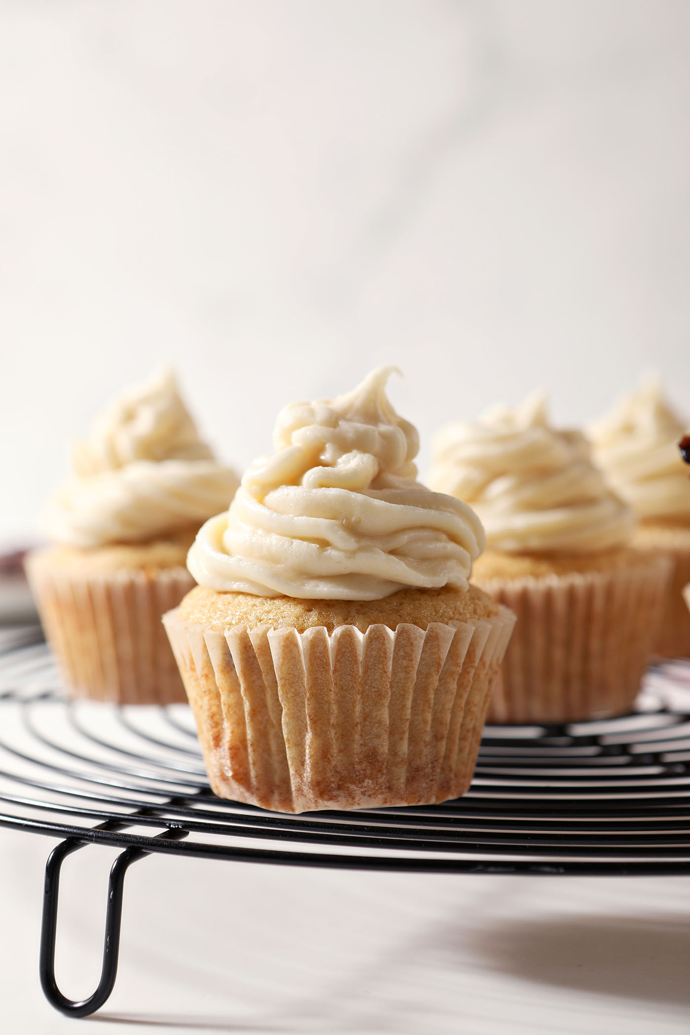 Bourbon Maple Bacon Cupcakes on a wire cooling rack above a marble surface