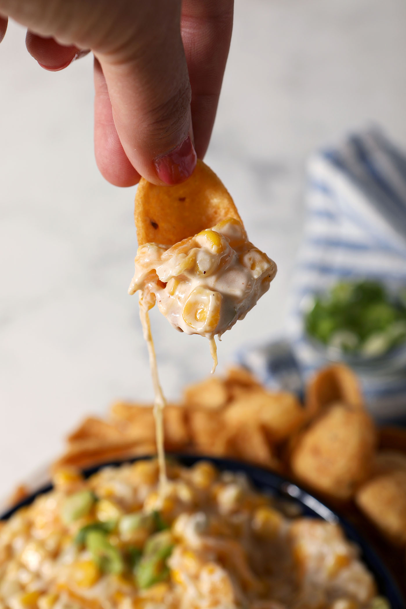 A chip scoops some Hot Corn Dip up from a bowl