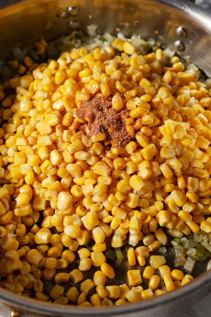 Corn and seasonings added to a pan, before stirring and cooking