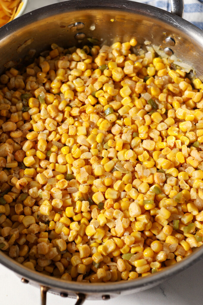 Corn and seasonings in a pan with sautéed veggies, after cooking