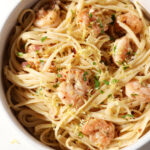 Close up of a bowl of lemon shrimp pasta garnished with extra parsley, lemon zest and red pepper flakes