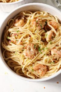 Close up of a bowl of lemon shrimp pasta garnished with extra parsley, lemon zest and red pepper flakes
