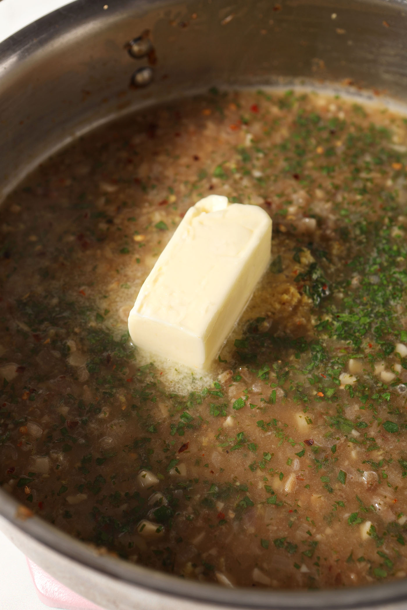 A stick of butter on top of the rest of the pasta sauce ingredients before cooking down