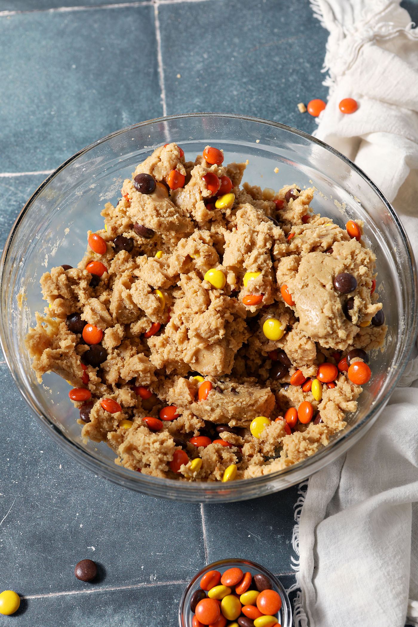 Reese’s Pieces Peanut Butter Cookie dough in a bowl on a blue tiled surface next to a white linen