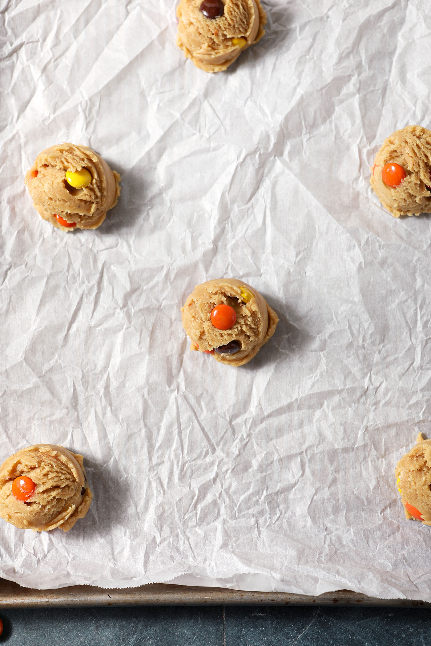 Scooped Reese’s Pieces Peanut Butter Cookie ought on a parchment-lined sheet pan