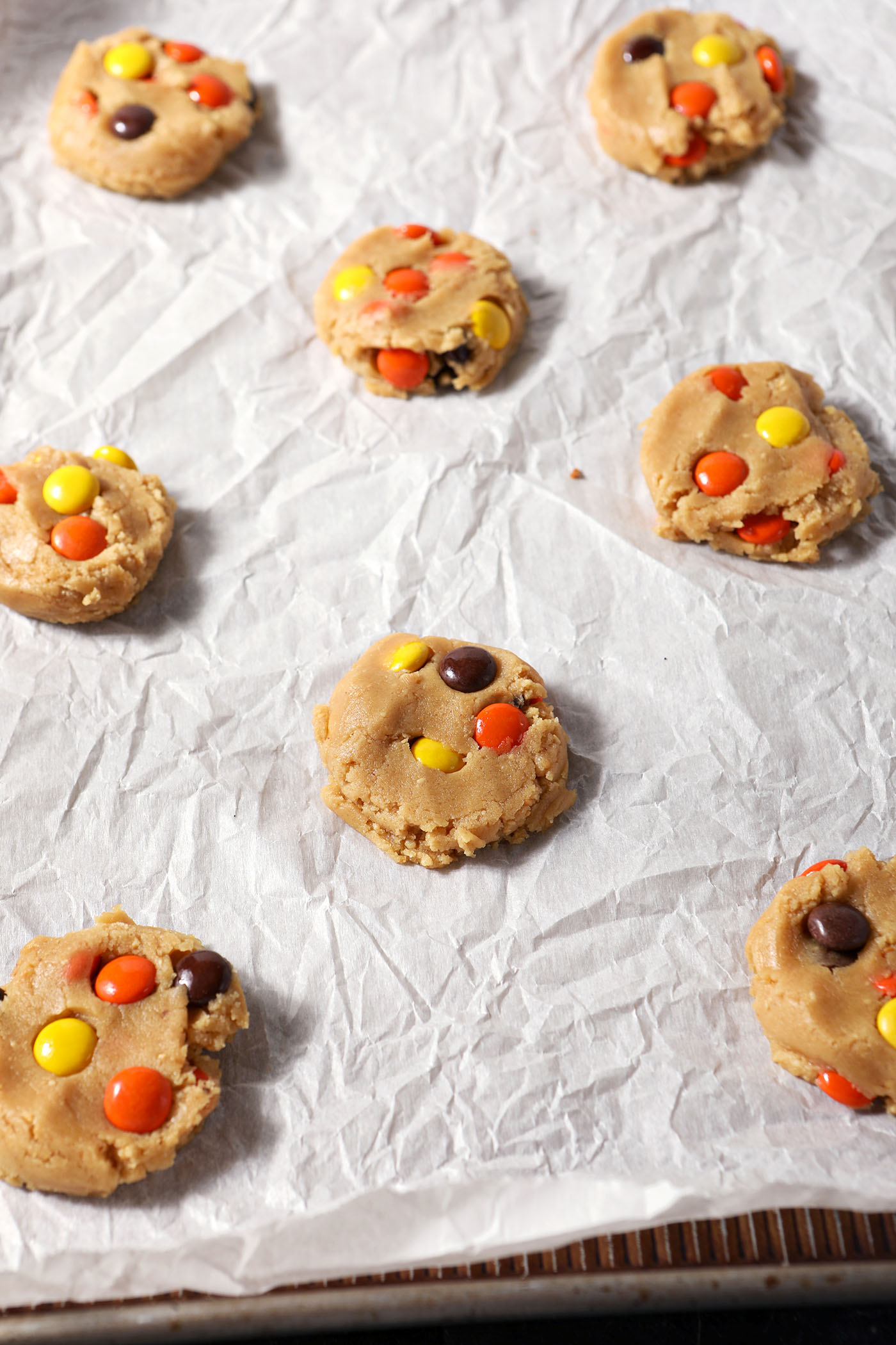 Flattened Peanut Butter Cookies with Reese’s Pieces on parchment before baking