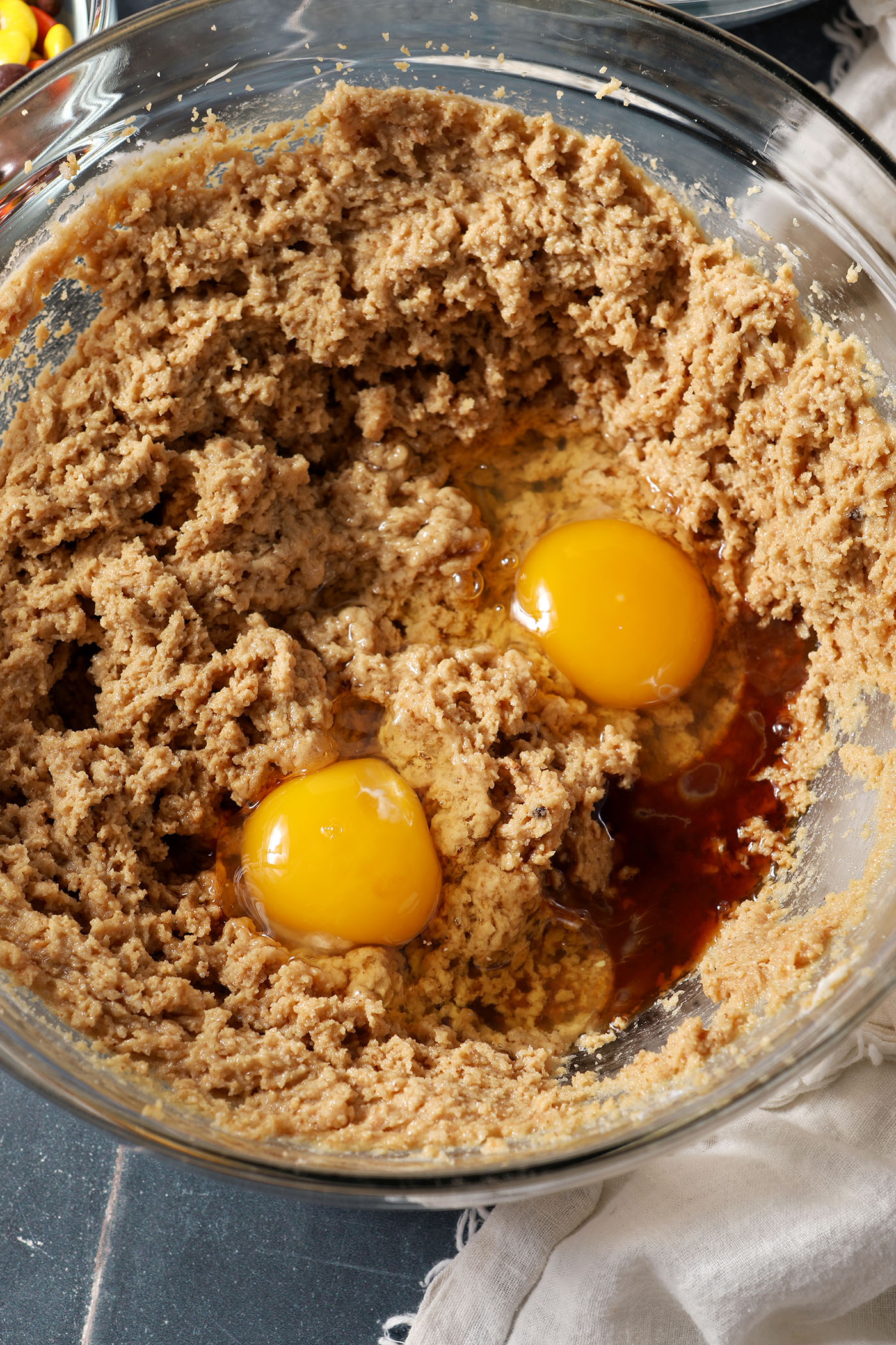 Eggs and vanilla extract sit on top of creamed sugars, peanut butter and butter in a bowl