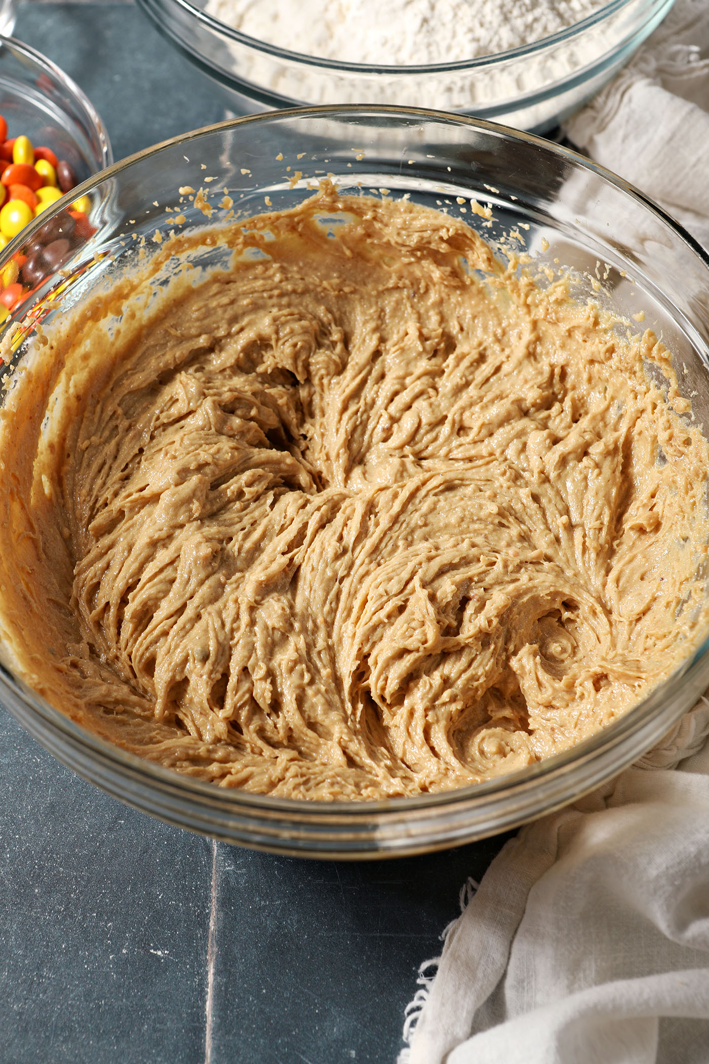 Wet ingredients whipped in a bowl for cookies on a dark blue tiled surface
