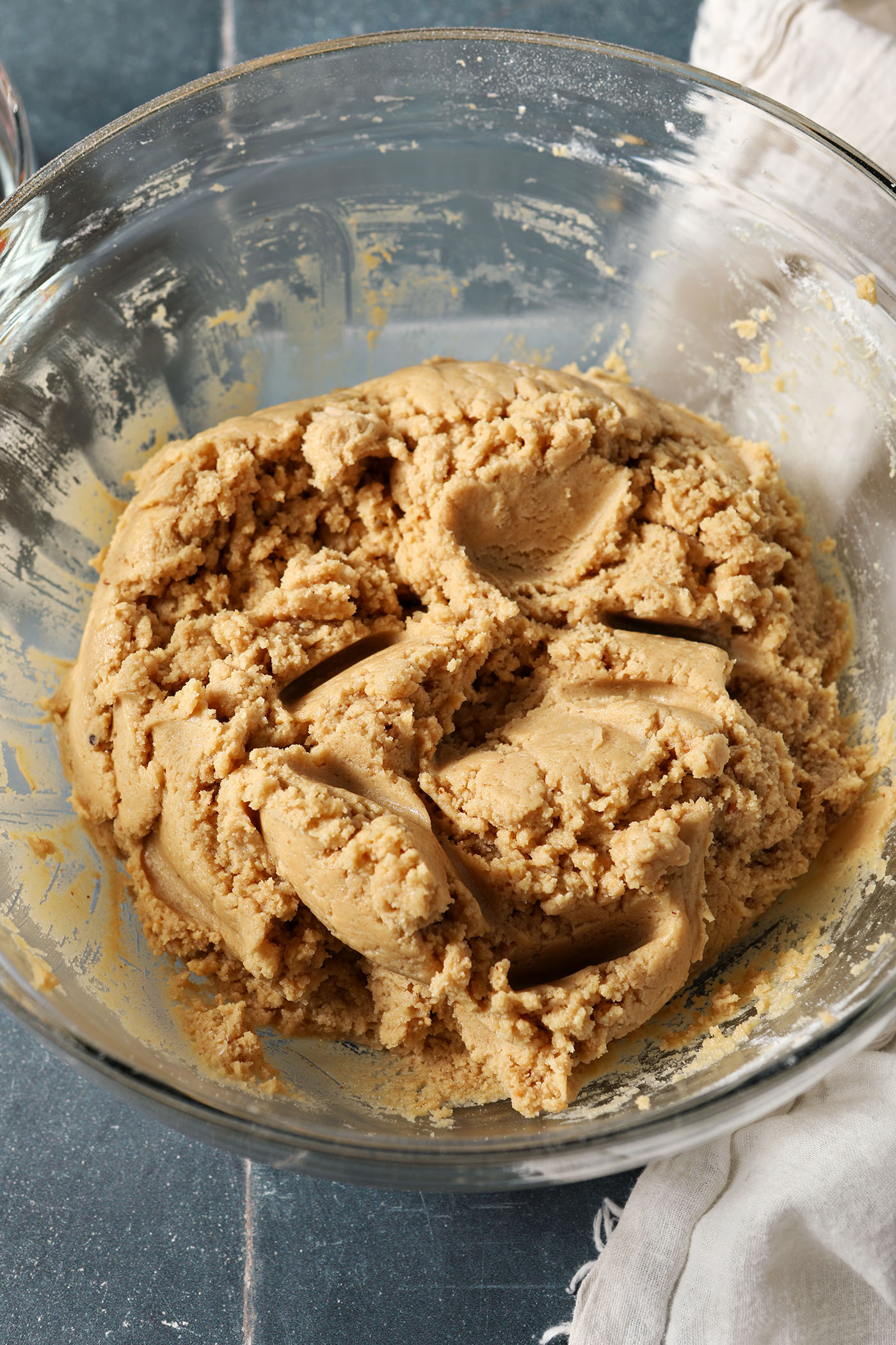 Blended cookie dough in a bowl on a blue surface next to a white linen