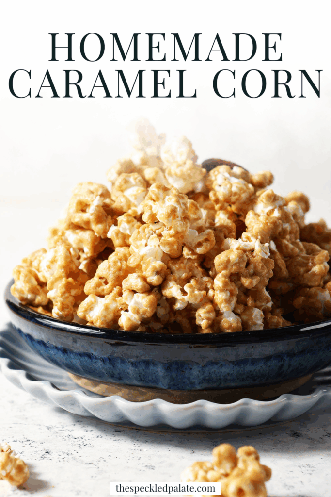 A blue bowl is heaped high with caramel corn on a stone surface, surrounded by caramel corn bits with the text homemade caramel corn