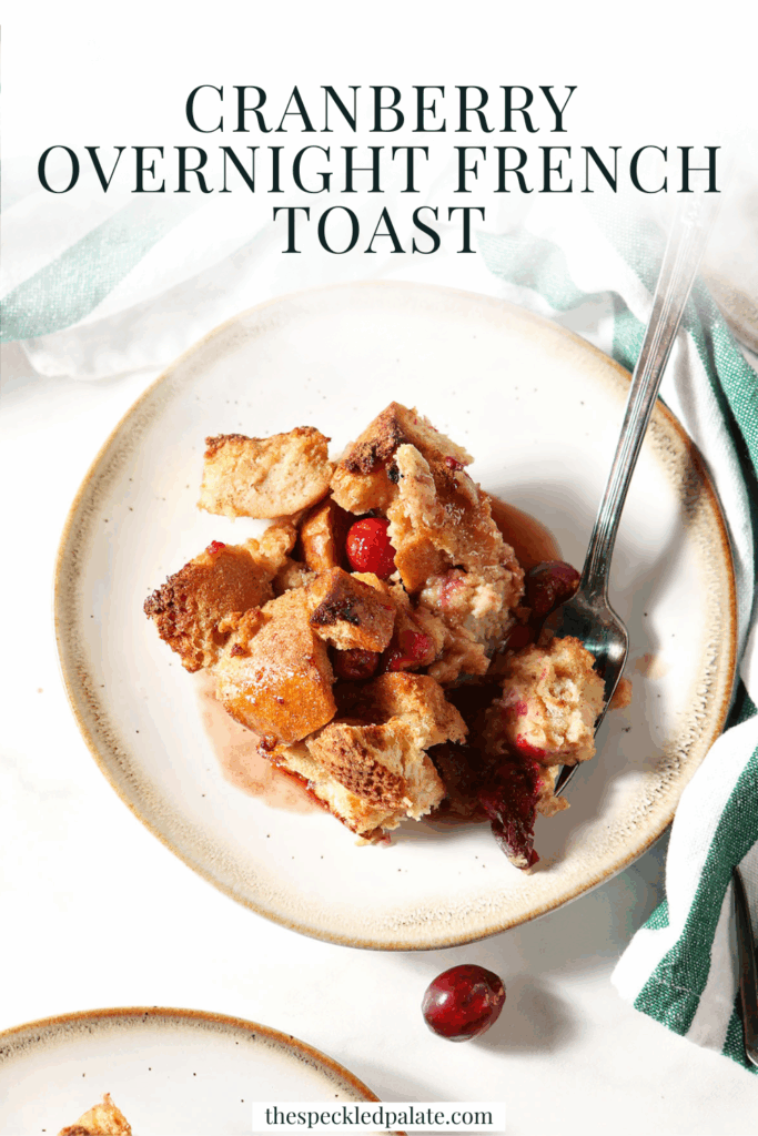 Overhead image of a plate of cranberry French toast casserole with a fork next to a green and white striped linen with the text cranberry overnight french toast