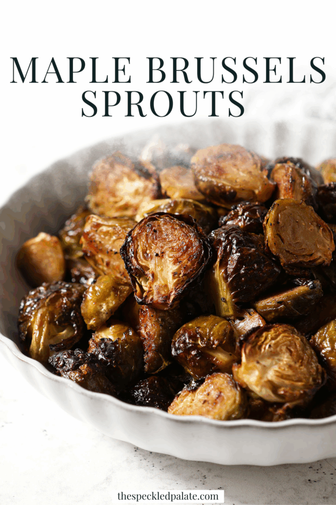 A bowl of Roasted Brussels Sprouts on a white surface with a spoon in it with the text maple brussels sprouts
