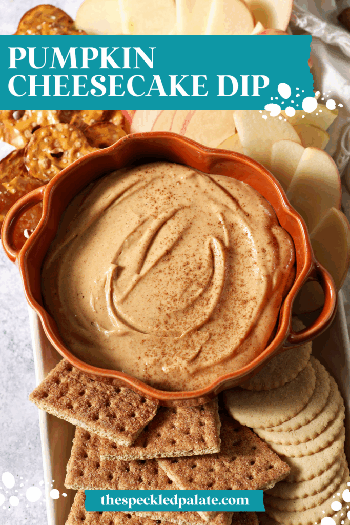 Close up of a pumpkin-shaped bowl holding Pumpkin Cheesecake Dip, surrounded by crackers and apple slices with the text pumpkin cheesecake dip