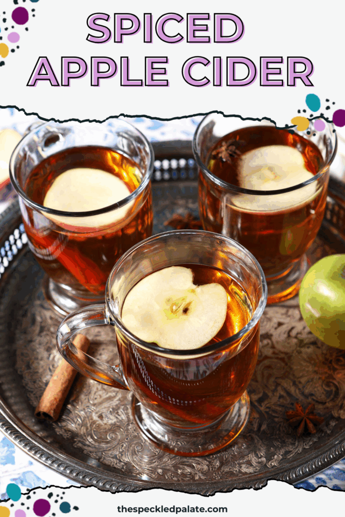 Close up of three glasses of hot cider topped with apple slices on a silver platter with the text spiced apple cider