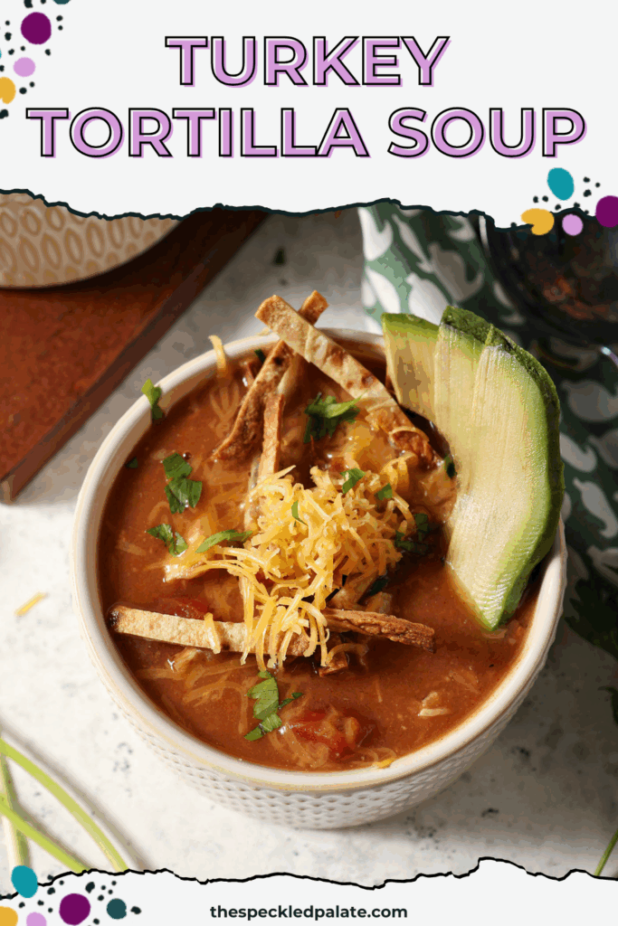 a bowl of a red soup from above, garnished with avocado slices, shredded cheese, cilantro and tortilla sticks, with the text turkey tortilla soup