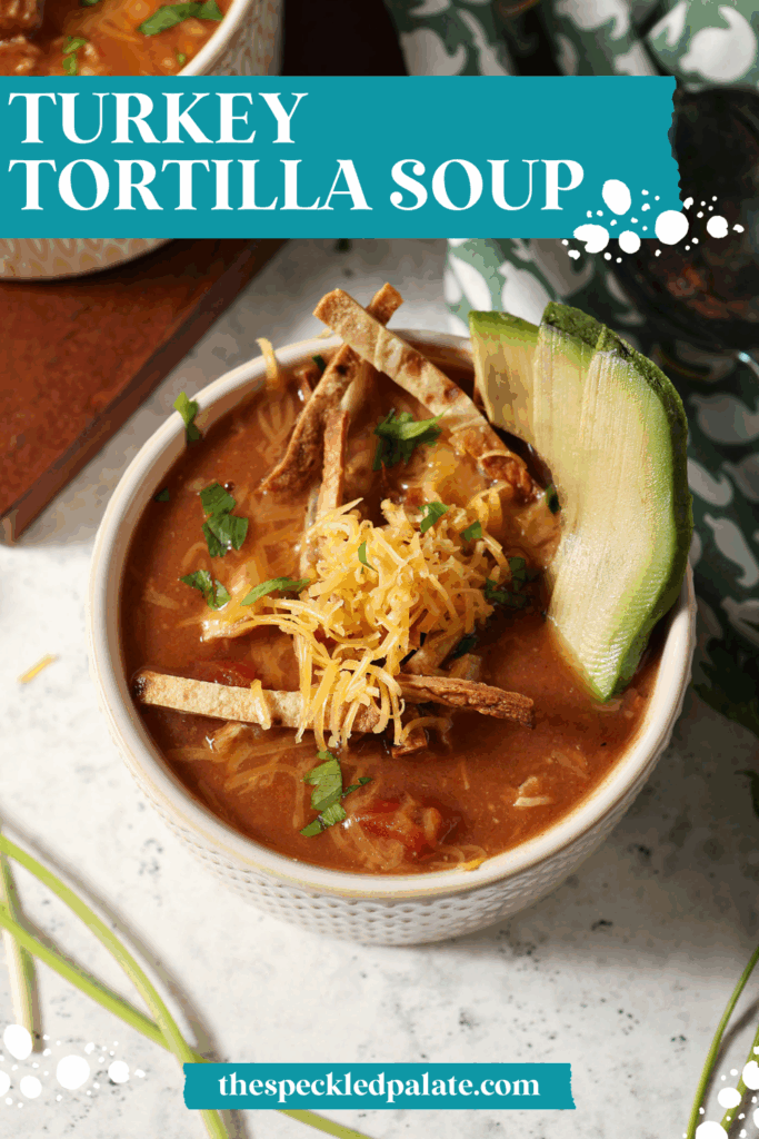 two bowls of red soup from above, garnished with avocado slices, shredded cheese, cilantro and tortilla sticks, with the text turkey tortilla soup