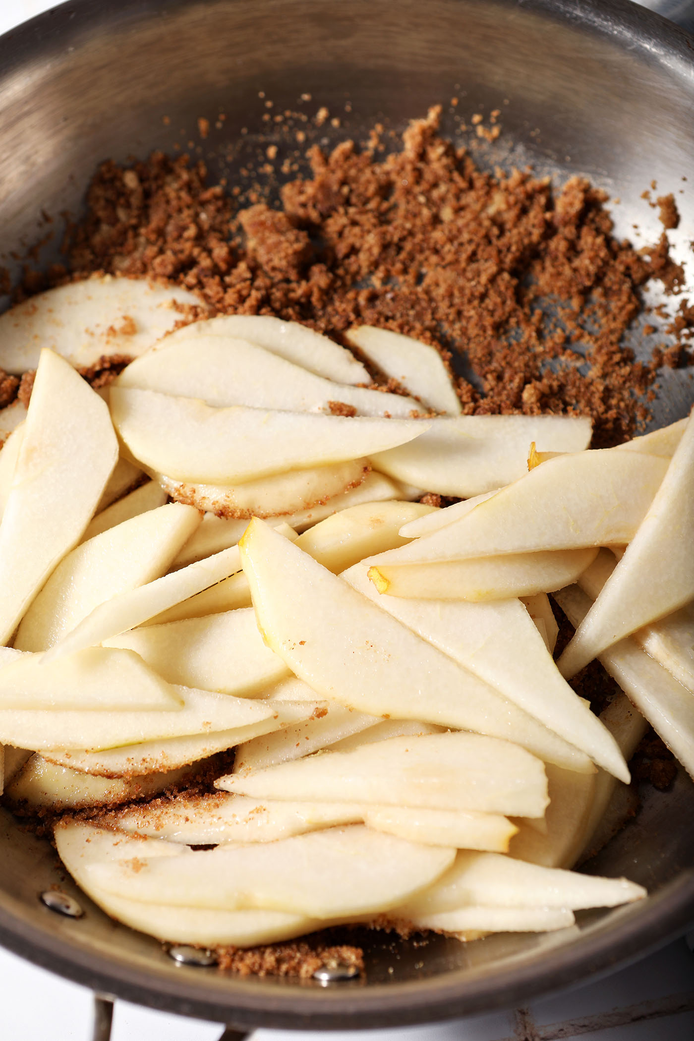 Sliced pears on top of sugar, spices and butter in a skillet