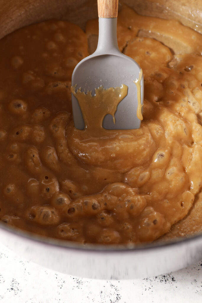 Boiling caramel in a dutch oven with a grey rubber spatula