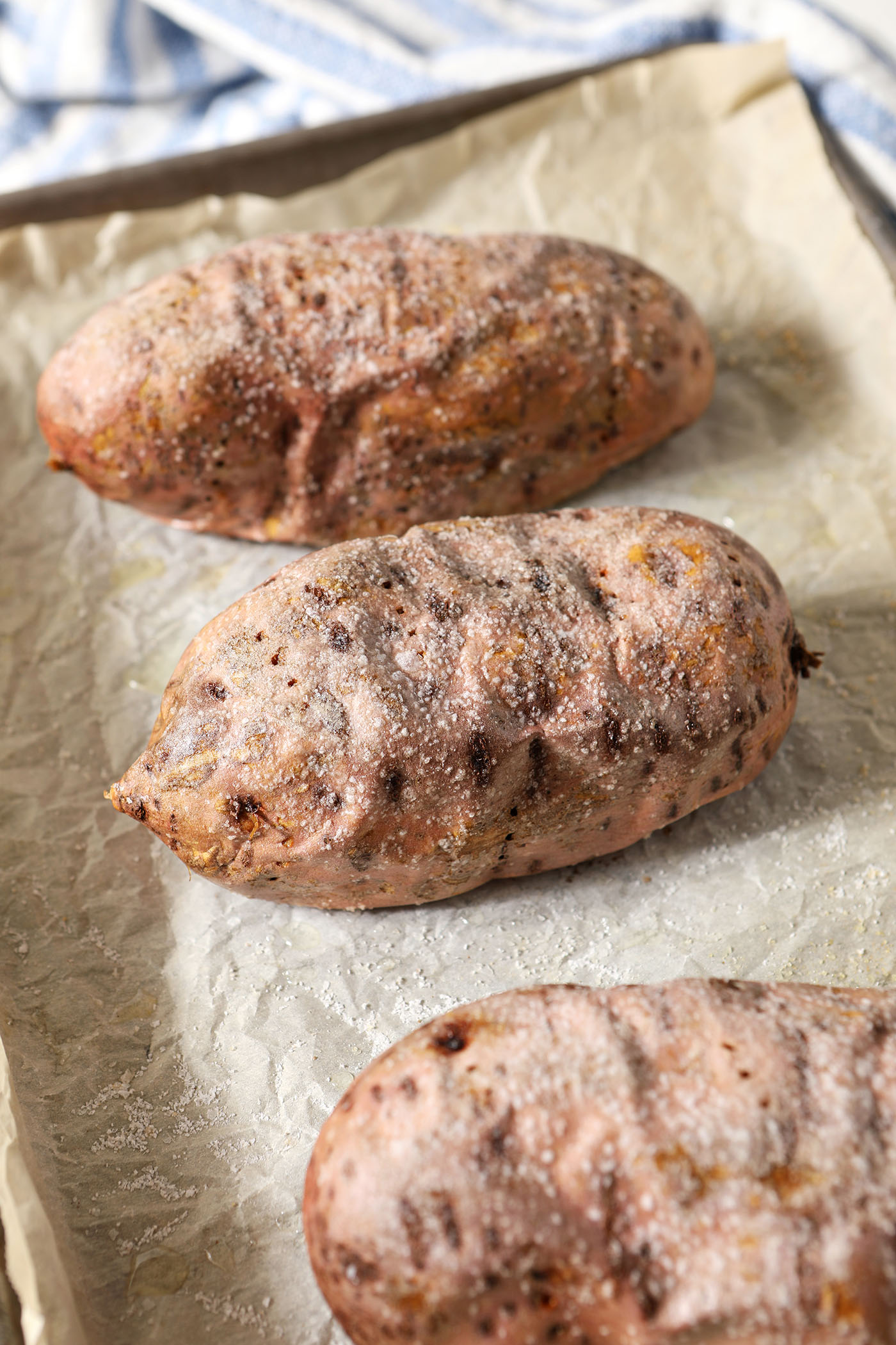 Three roasted sweet potatoes on a sheet pan