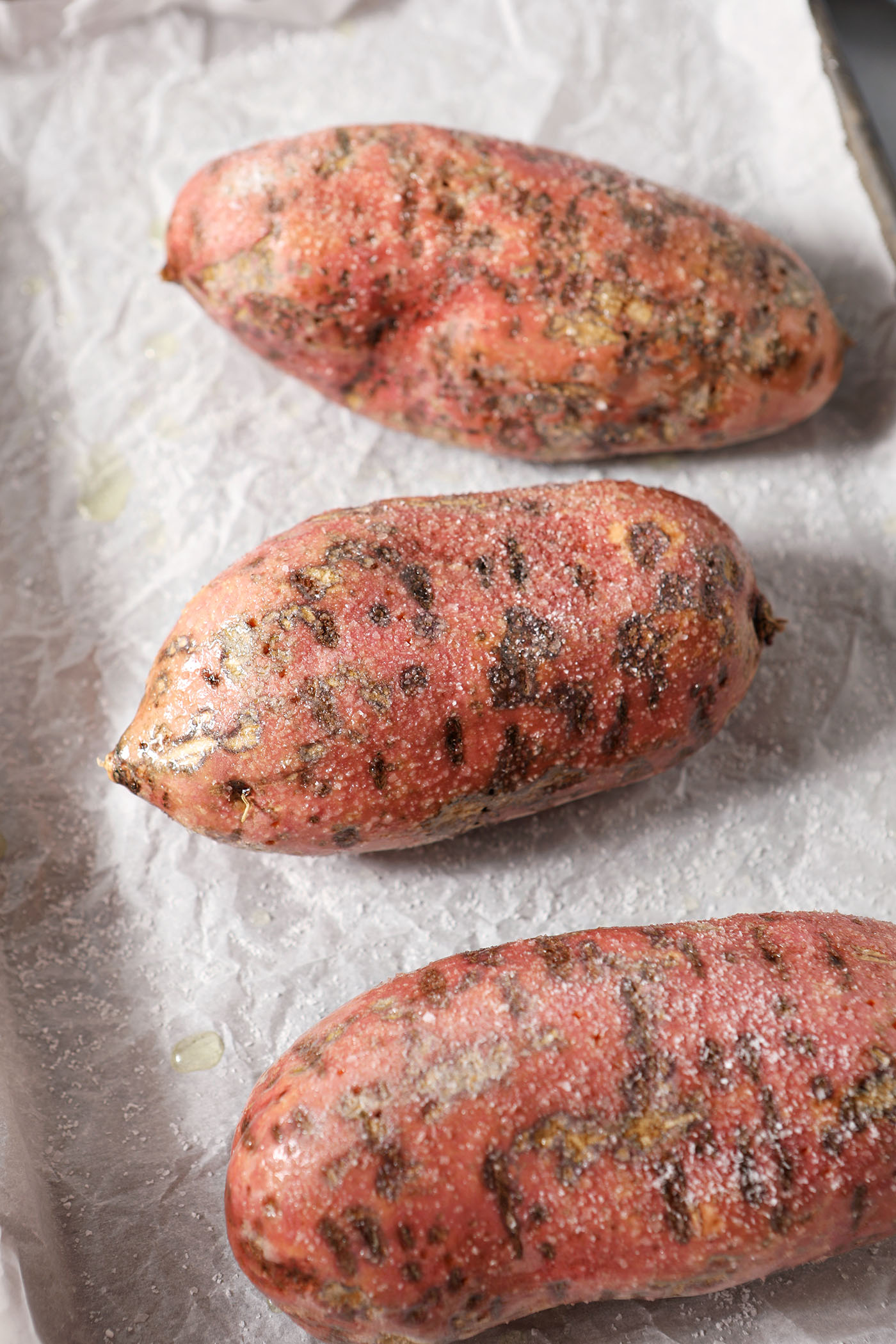 Salted and oiled sweet potatoes on a sheet pan, before roasting