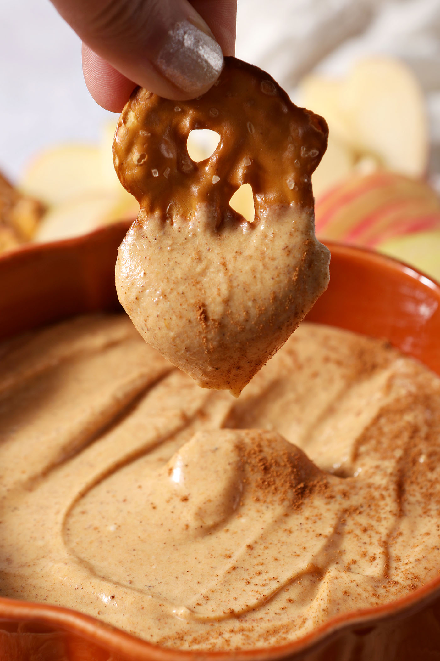 A pretzel dips into sweet pumpkin dip