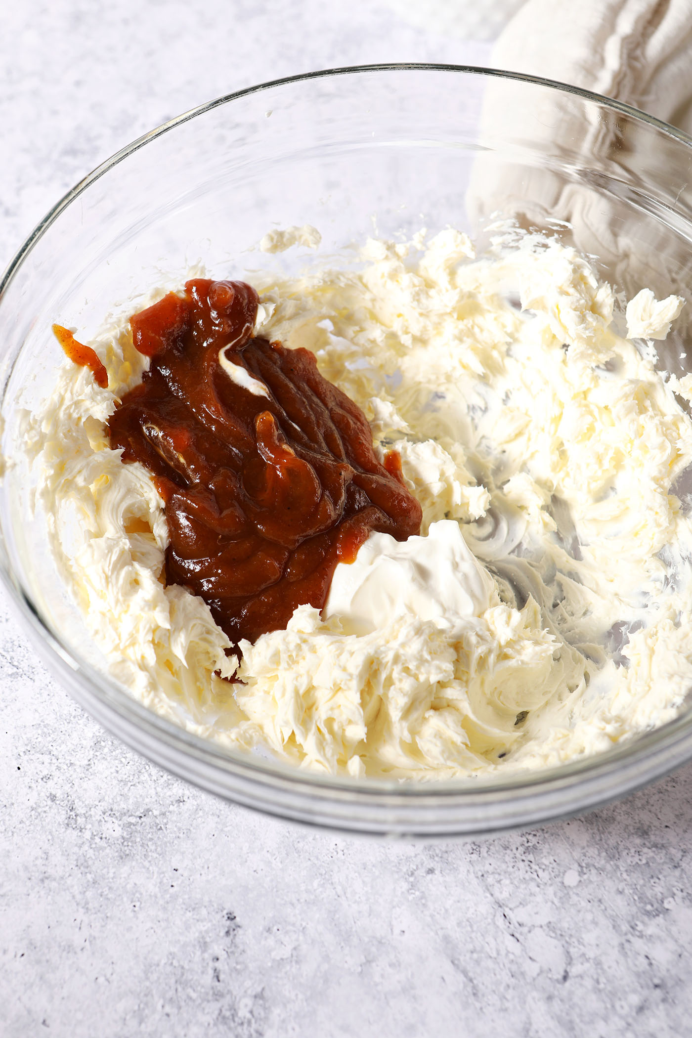 Sour cream and pumpkin butter on top of whipped cream cheese in a large glass bowl