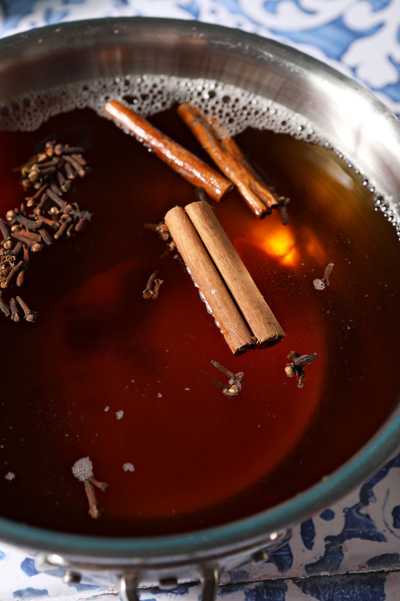 Close up of whole spices floating on top of cider in a saucepan