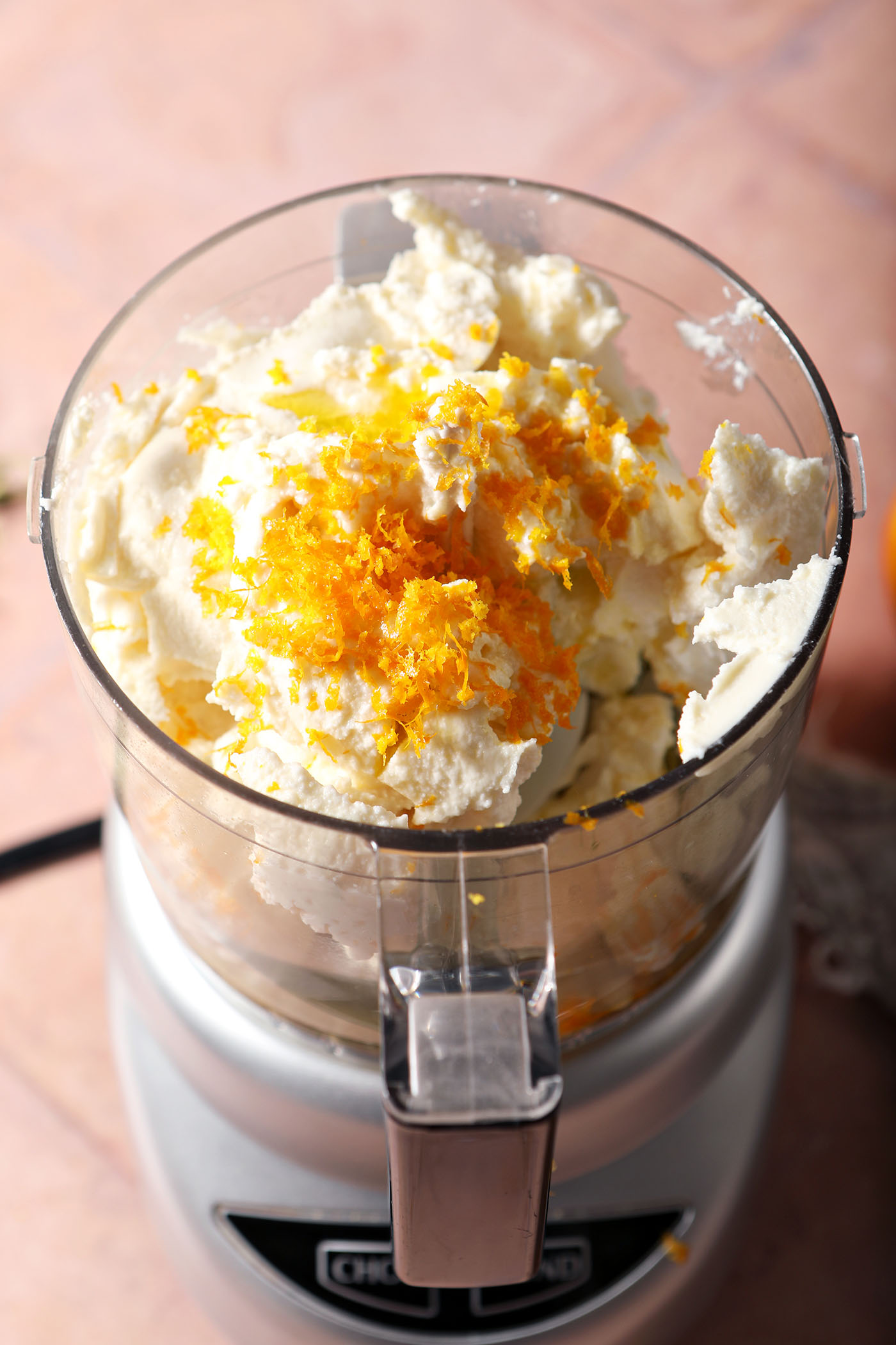 Ricotta cheese in a food processor with orange zest and oil, before blending