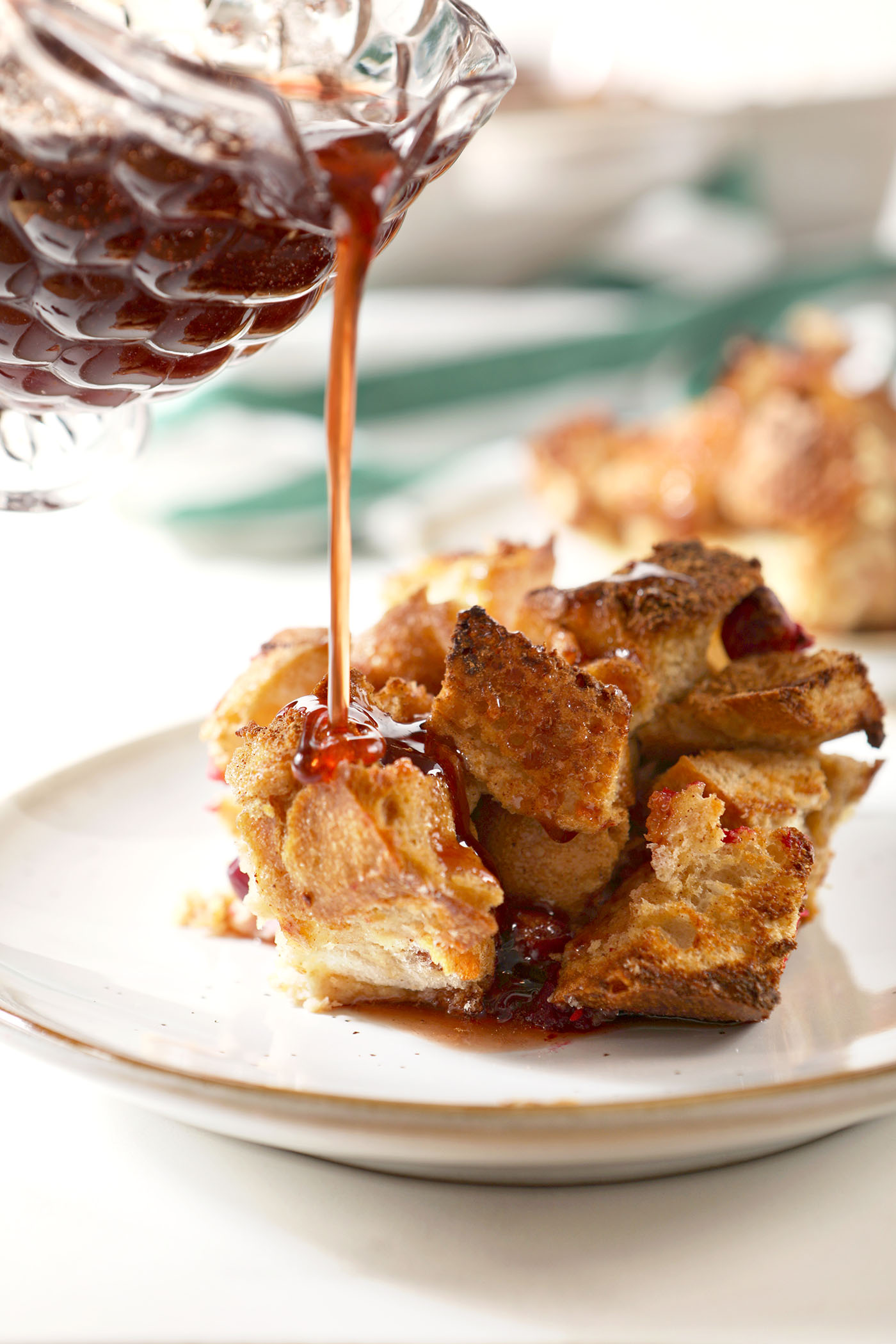 Cranberry syrup pours on top of a serving of cranberry French toast casserole