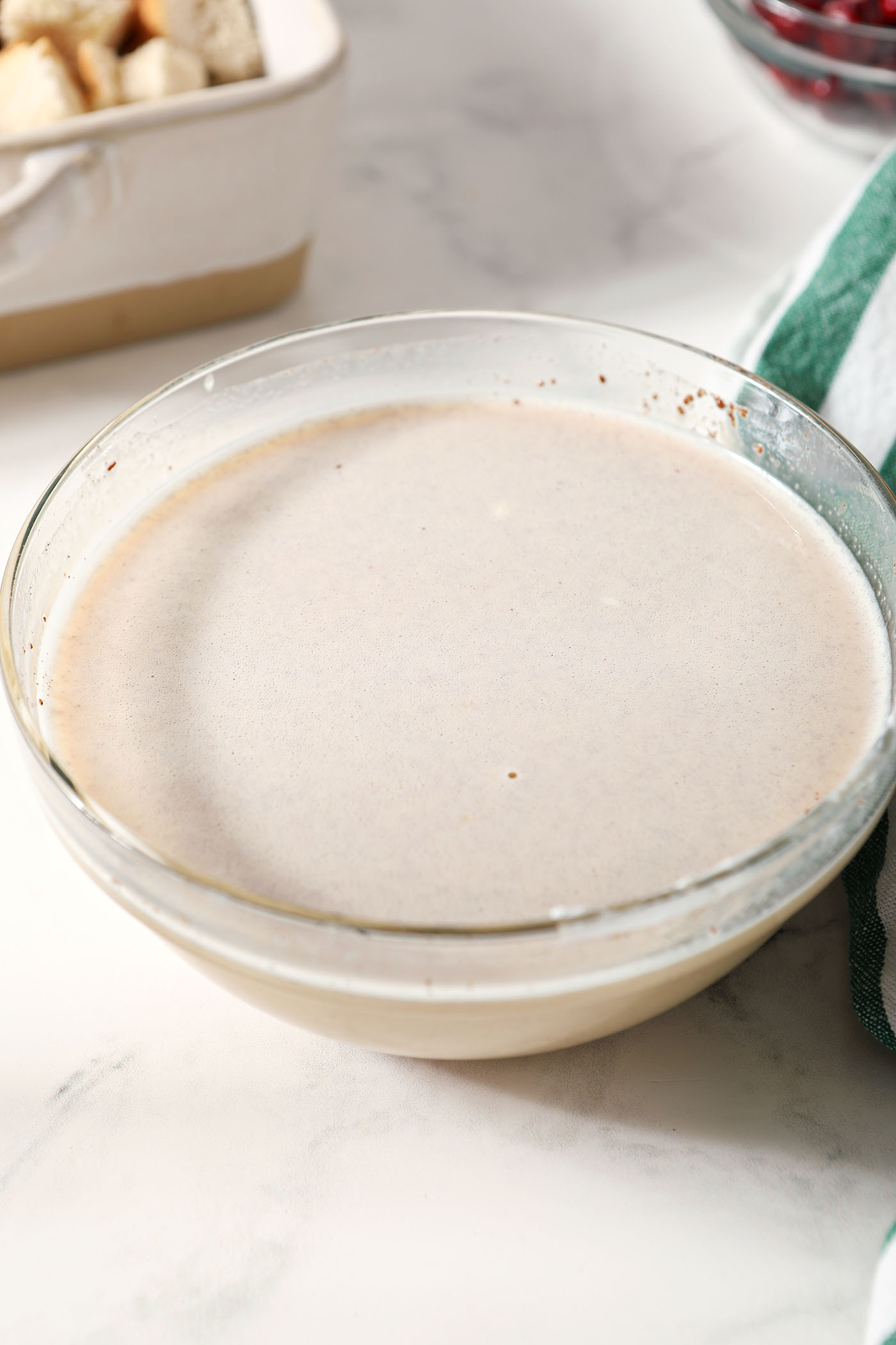 French toast custard in a bowl next to a green and white linen
