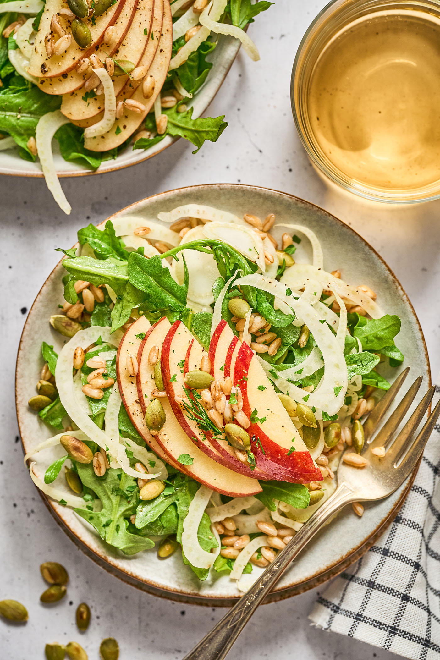 Overhead of a place of apple fennel salad with farro surrounded by pepitas and apples