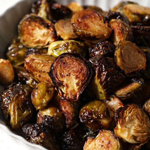 Close up of a scalloped grey bowl holding roasted maple Brussels sprouts