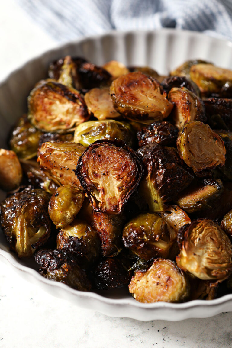 Close up of a scalloped grey bowl holding roasted maple Brussels sprouts