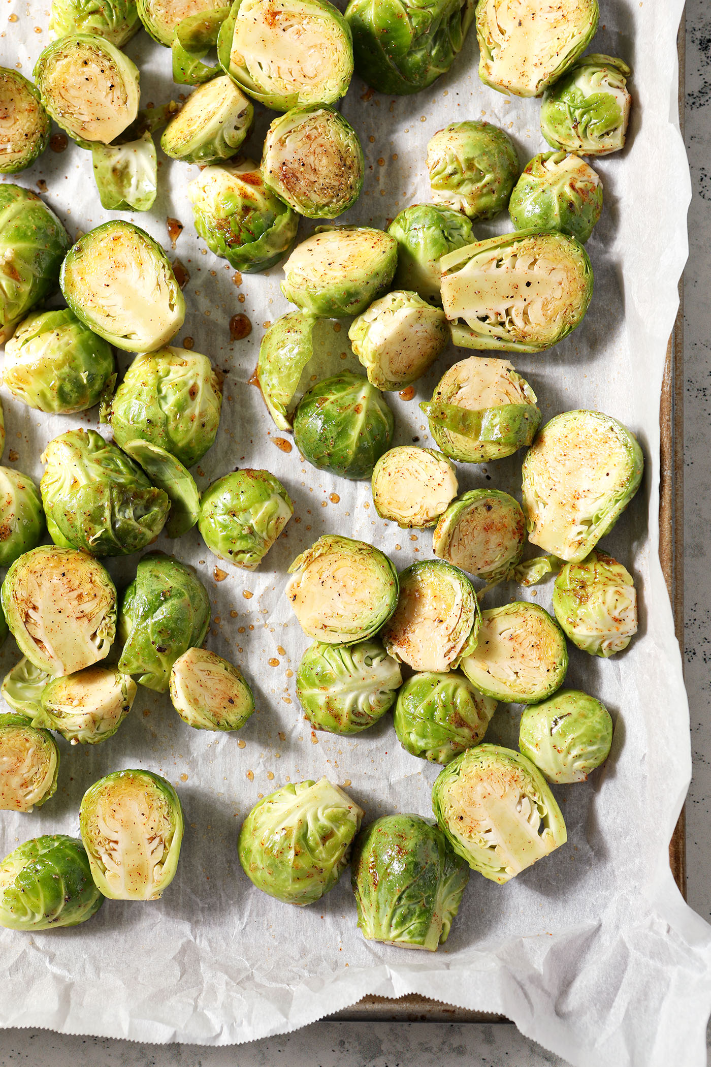 Seasoned brussels sprouts on a sheet pan before roasting