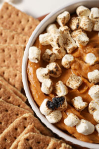 Overhead of a bowl of Sweet Potato Pie Dip topped with toasted marshmallows and surrounded by graham crackers