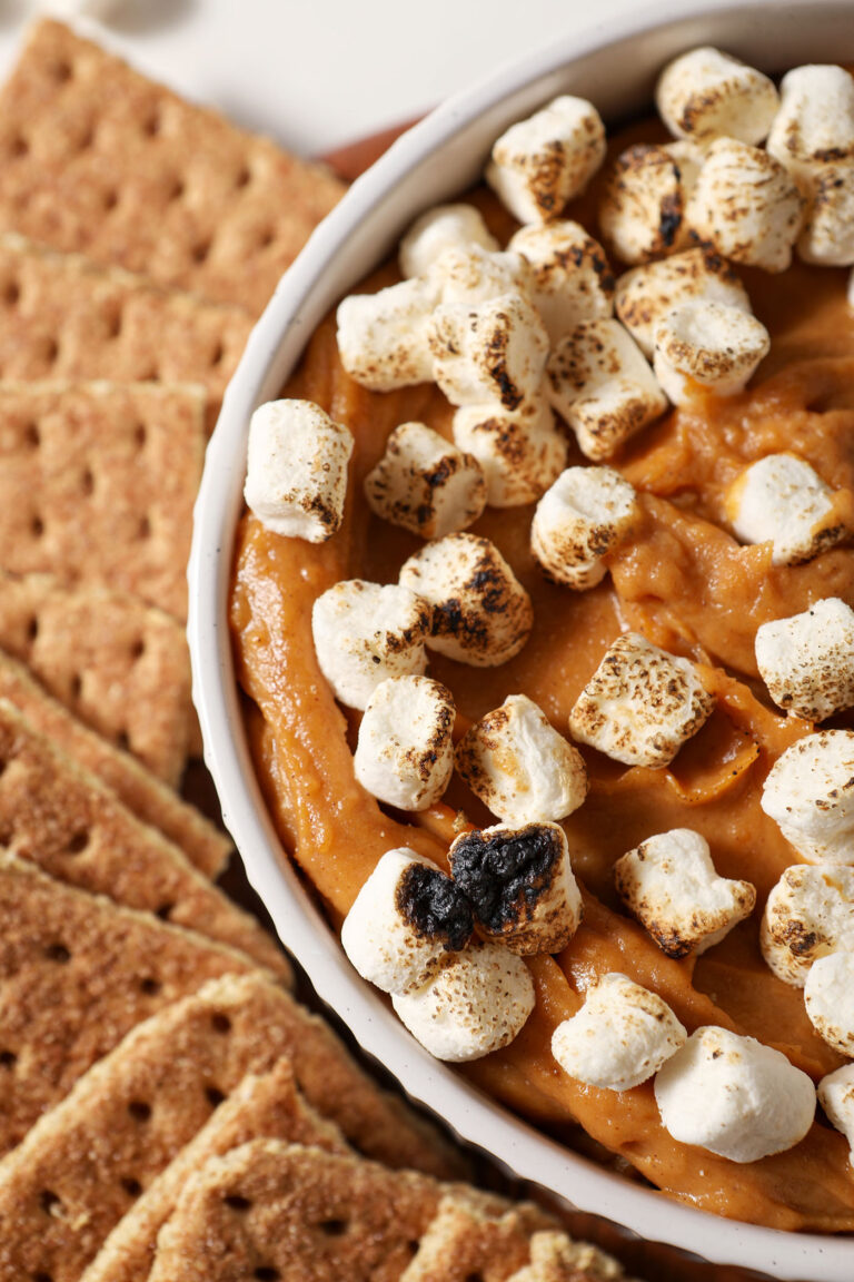 Overhead of a bowl of Sweet Potato Pie Dip topped with toasted marshmallows and surrounded by graham crackers
