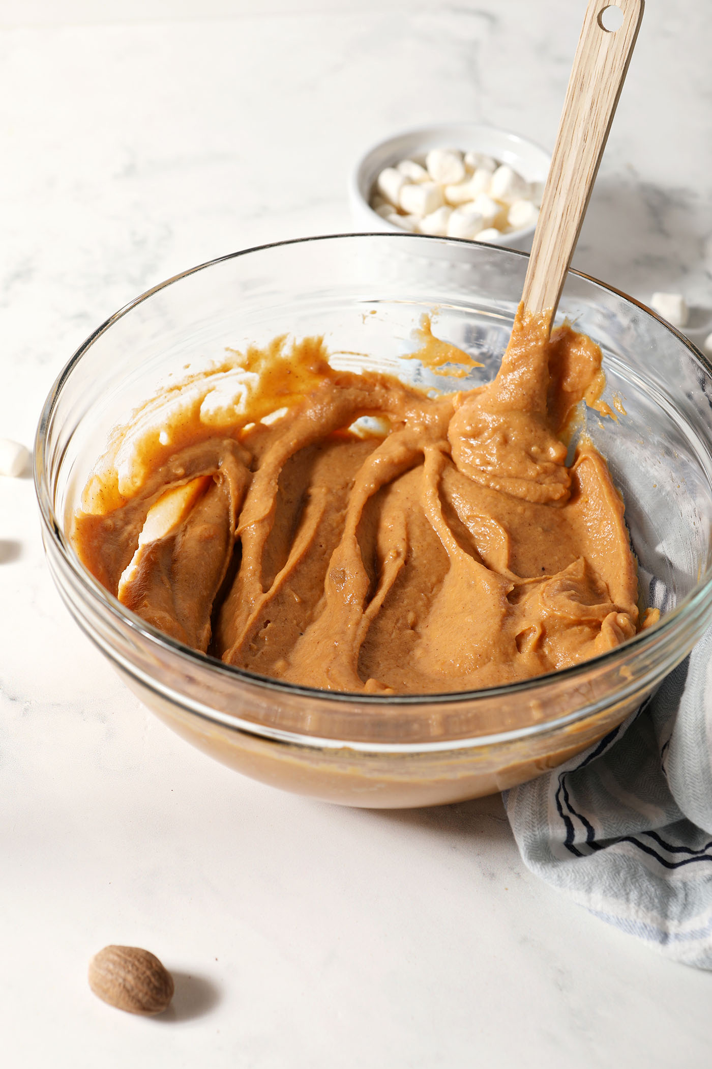 Mixed sweet potato dip in a bowl on a white surface next to a blue linen