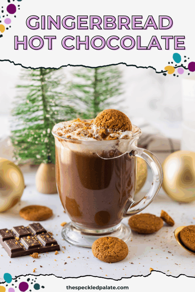 Closeup of a mug of gingerbread hot chocolate on a white surface surrounded by Christmas decor and ingredients with the text gingerbread hot chocolate