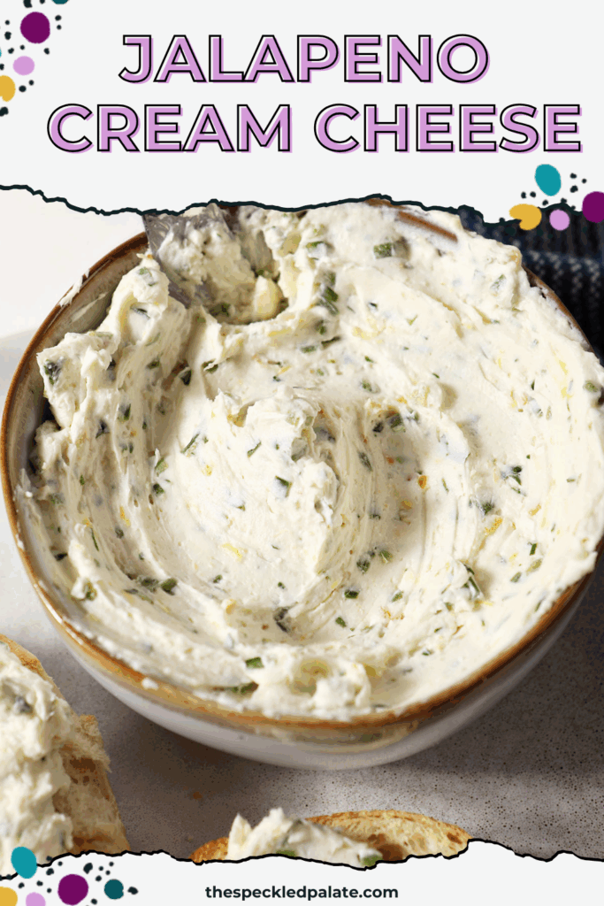 Close up of a bowl of jalapeño cream cheese on a marble surface next to a blue linen with the text Jalapeno Cream Cheese