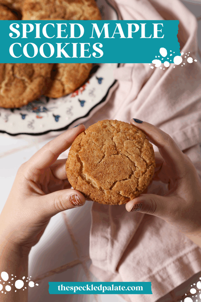 A child holds a spiced maple cookie in her hands above a platter of more cookies on a white tile surface with the text spiced maple cookies