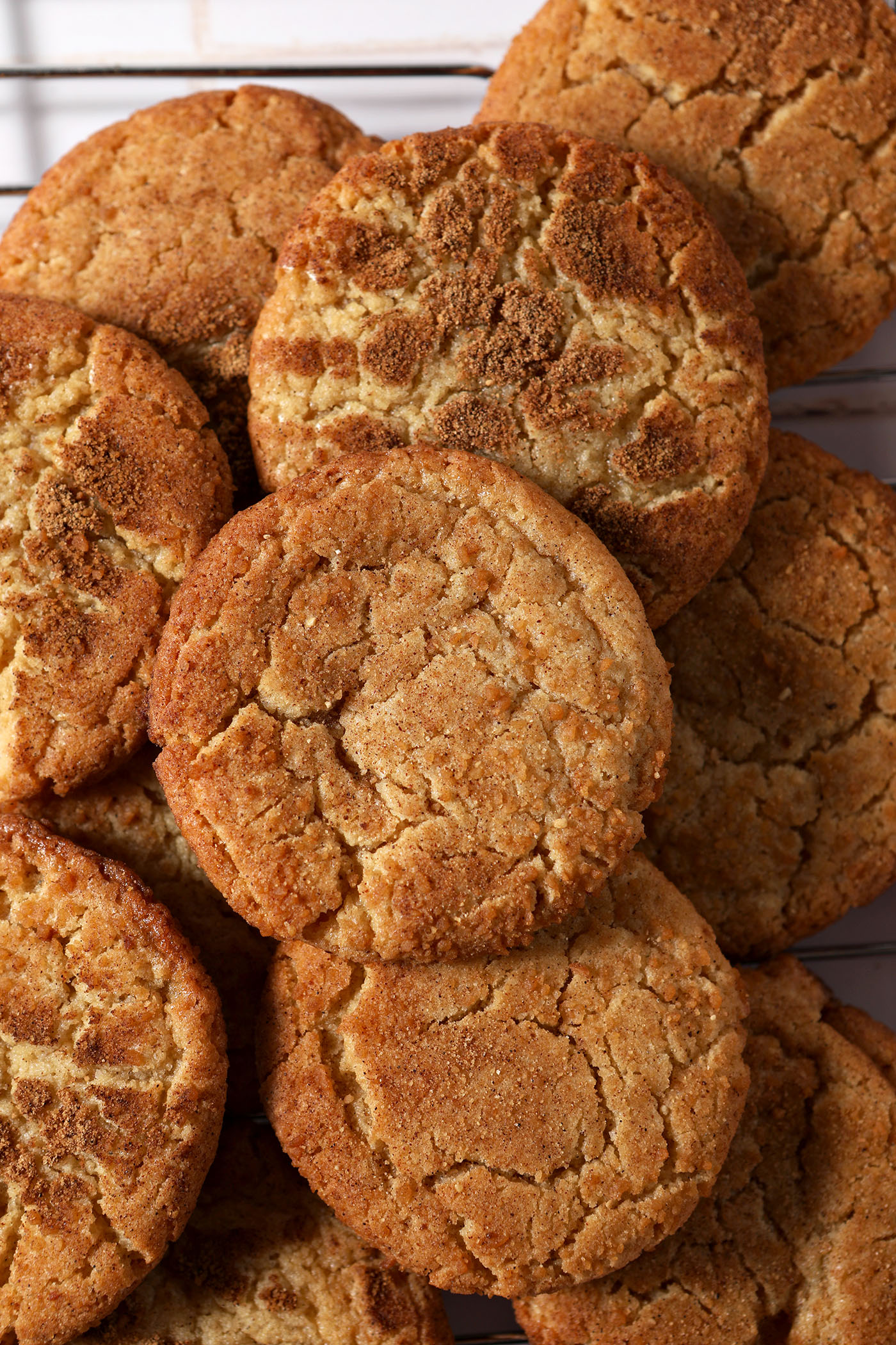Ginger maple cardamom cookies stacked on top of each other on a cooling rack