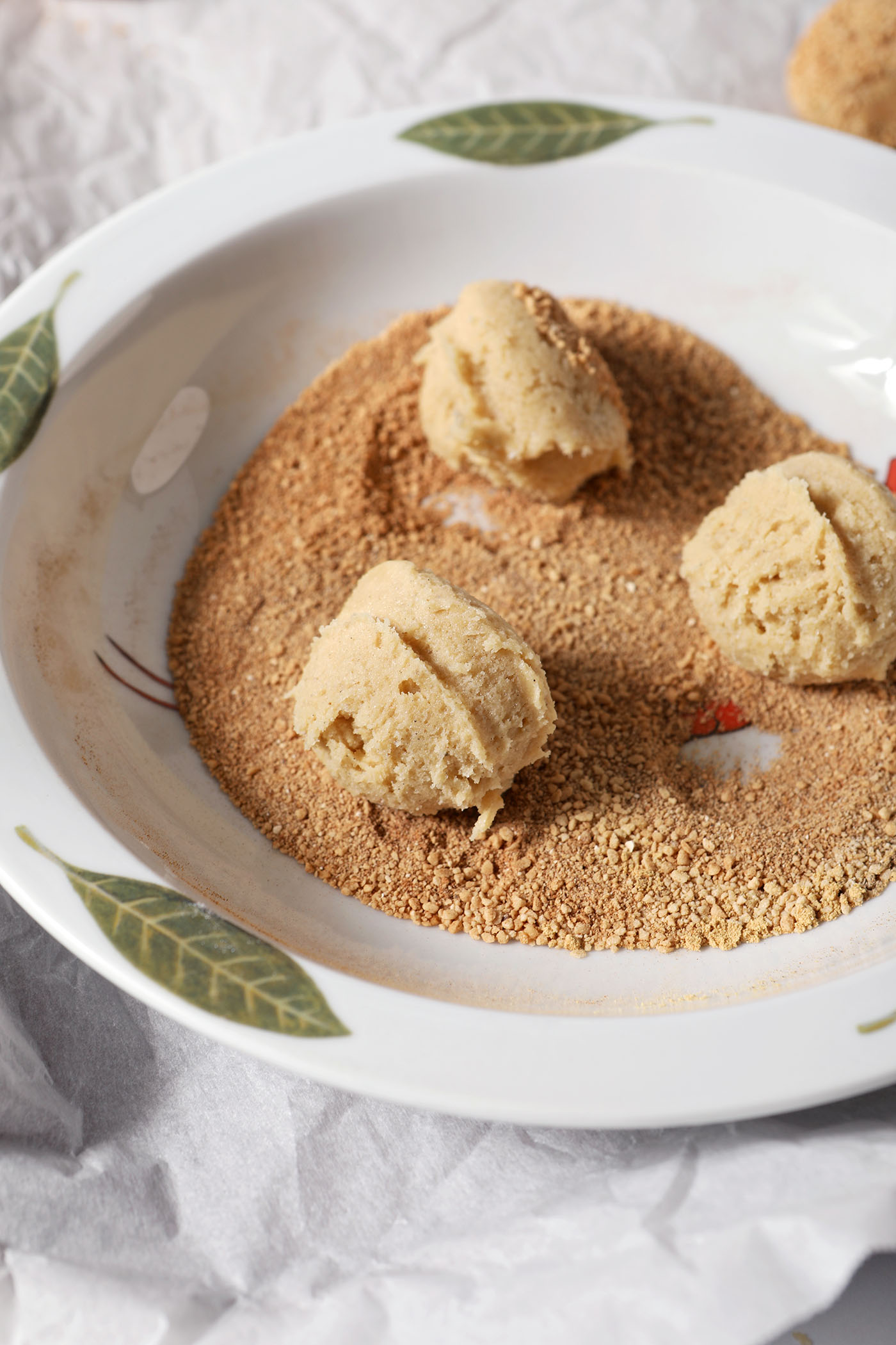 Cookie dough balls in a sugar-spice mixture before rolling